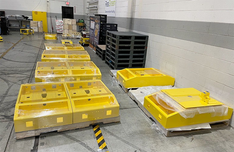 Yellow AGV chassis components on pallets waiting to be assembled.