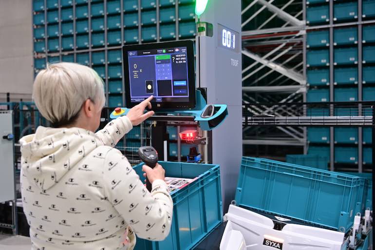 A human picking product out of a bin on top of a mobile robot from Exotec.