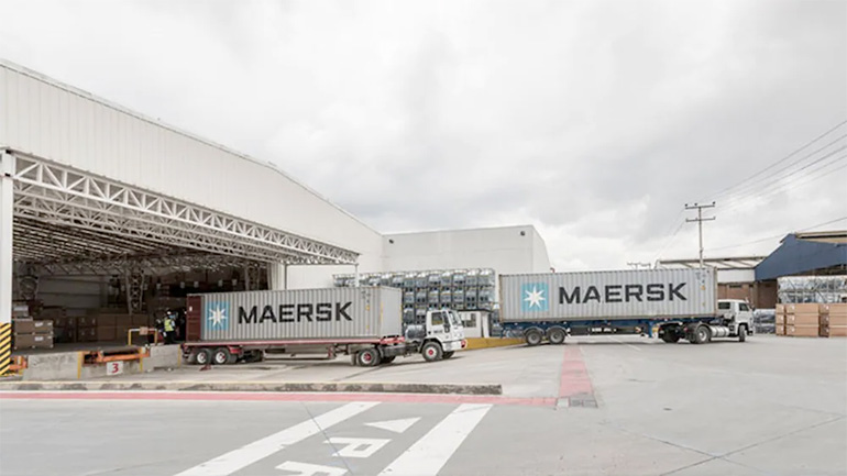 Maersk tractor trailers queue at a Maersk warehouse loading dock.