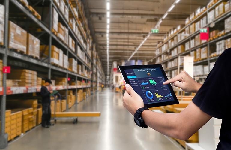 A person holding a tablet with various metrics displayed on the screen, with a warehouse in the background. Pallet offers software to manage all of this.