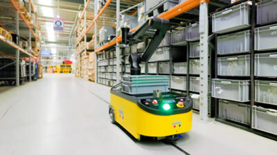 mobile robot with a kassow cobot mounted on top, in a warehouse aisle.