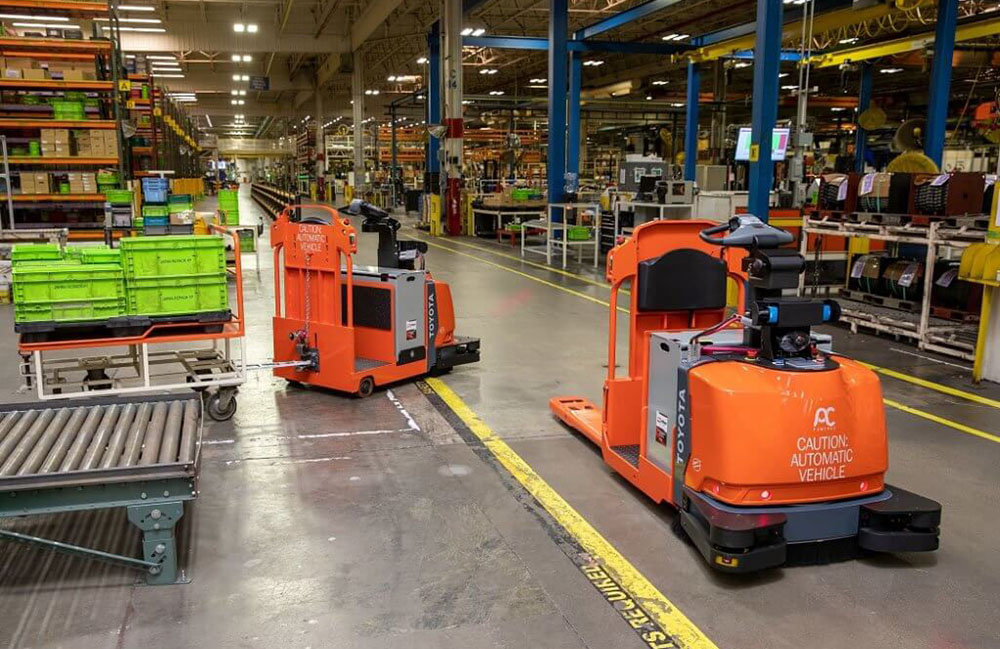 Two orange automated guided vehicles from Toyota Material Handling and Raymond Corp. in a warehouse.
