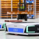 Two Geek+ mobile robots with Korber branding in a warehouse. Infios now provides warehouse software.