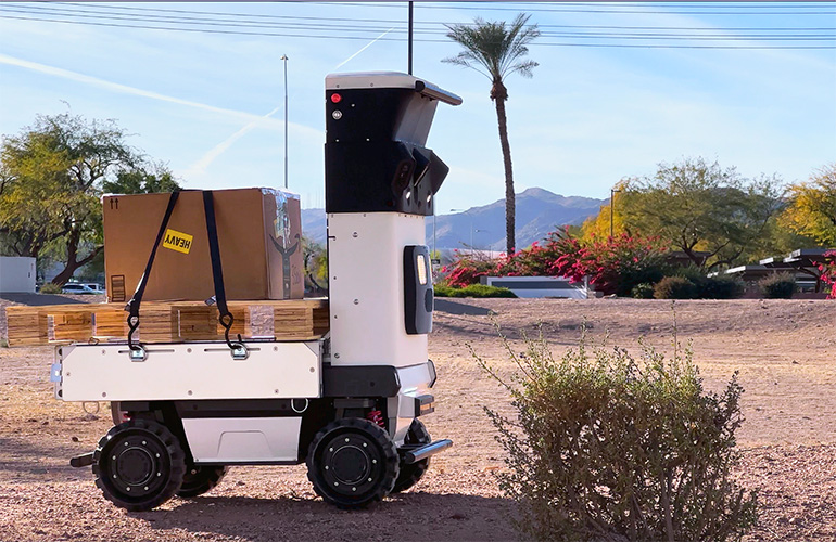 The Cartken Hauler driving across a desert with boxes.