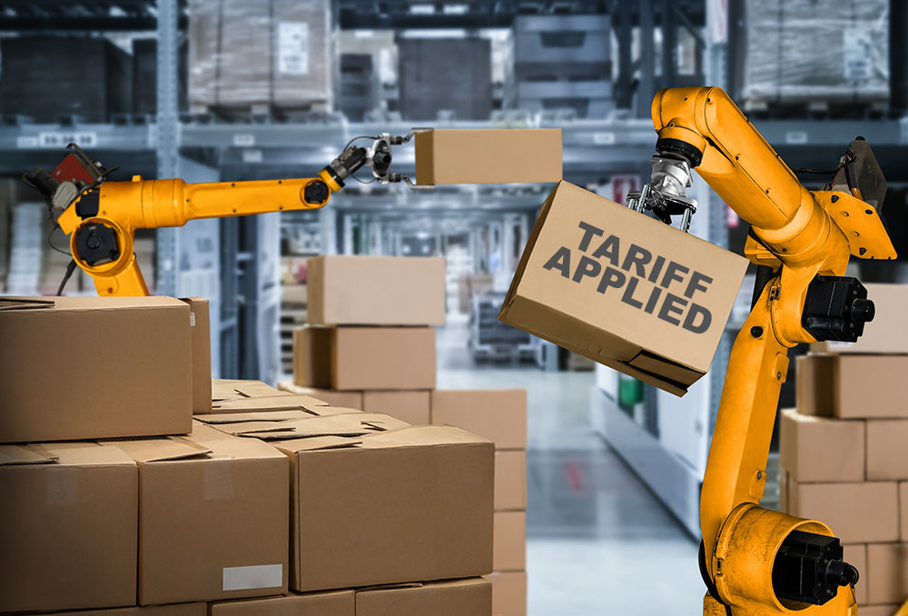 A robot arm sorting boxes, the one it is holding says "TARIFF APPLIED." Interact Analysis predicts that tariffs will slow investment but increase demand for warehouse automation.