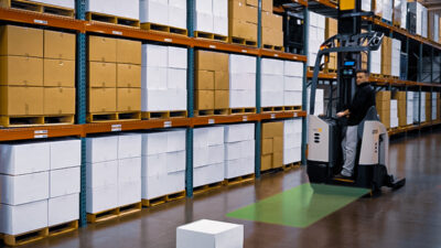 A forklift approaching a box in a warehouse with a green box showing ProximityAssist's view.