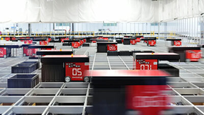 An image of the top of an AutoStore ASRS where you can see robots zipping across the top of the structure.