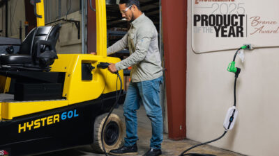 A person plugging in a Hyster forklift for charging.