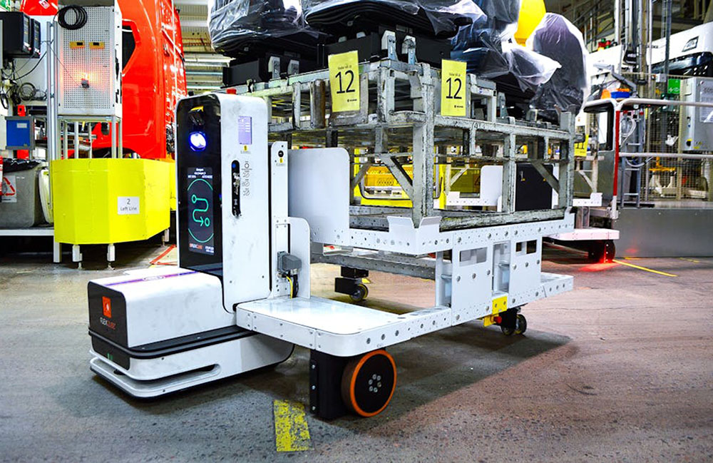 A FlexQube AMR carries automotive parts in a customer facility.