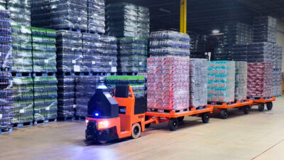 Cyngn's DriveMod tugger pulling boxes in a warehouse.